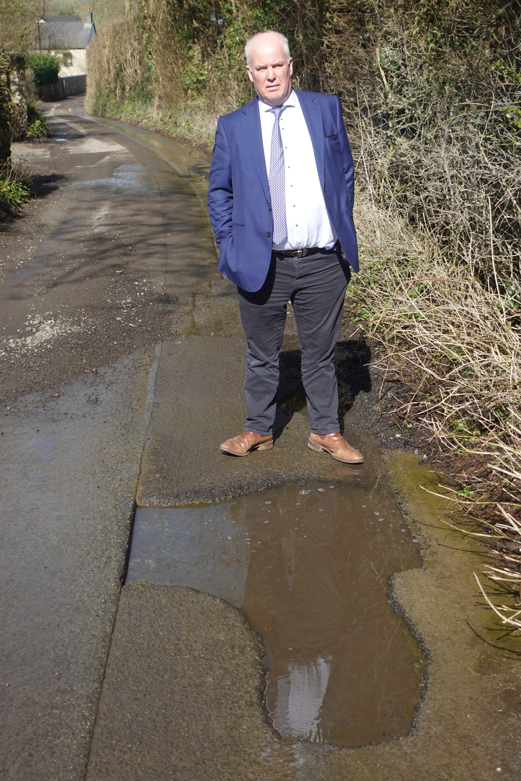Andrew RT Davies stands next to a deep pothole in Llancarfan